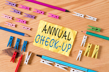 Text sign showing Annual Checkup. Business photo showcasing yearly reproductive health visit with a health care provider Colored clothespin papers empty reminder wooden floor background office
