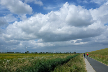 Ostfriesische Landschaft an der Nordseeküste mit Radtouristen - Stockfoto