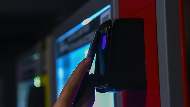 Close up view of woman paying for purchase at snack vending machine using smartphone. Contactless payment theme.