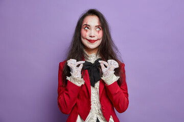 Halloween concept. Pleased woman with spooky makeup wants to look scarying adjustes bowtie wears...