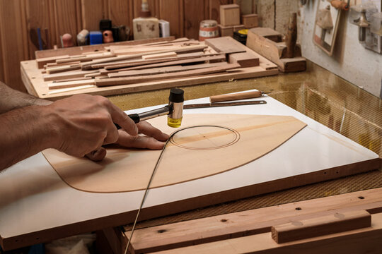 a luthier - instrument maker - inlaying ebony wood strips on the surface of soundboard to give point to whole outlines, guitar rosette.