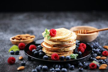 Homemade crepes served with fresh raspberrries and powdered sugar on rustic table.