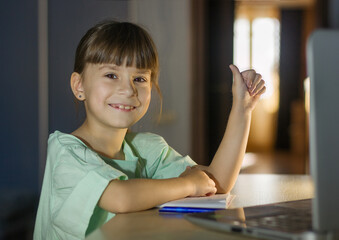 Distance learning education. Happy girl learn english language online with laptop at home. Little girl shows a like