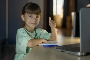 Poster Onderwijs op afstand. Gelukkig meisje leert Engels online met laptop thuis. Kleine meid laat een like zien © Albert Ziganshin