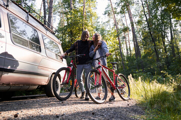 Couple embracing while standing with their bicycles