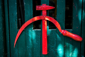 Hammer and sickle against the backdrop of a green wooden fence.