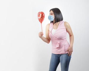 woman wearing mask in studio looking a red balloon heart