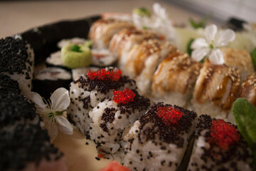 sushi rolls on a plate decorated with cherry flowers close up