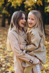 Fototapeta premium Happy mother and her beautiful daughter have fun and walk in the autumn park.