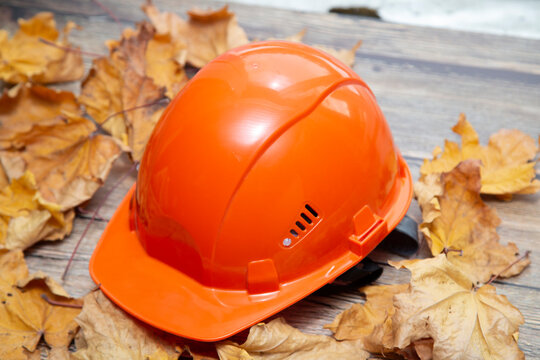 Protective helmet on a wooden background with yellow leaves.