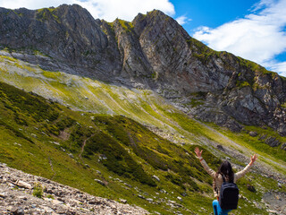 Naklejka na ściany i meble Unity with nature, a young female tourist in the mountains. Arms out to hug the horizon.
