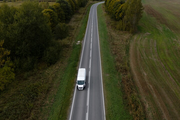 A white delivery van is driving on an asphalt road. © Amerigo_images