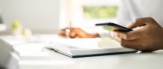 African Man Organizing Appointment Schedule Using Cellphone