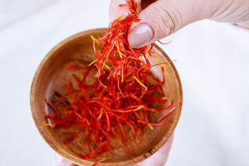 The girl in gloves takes the saffron from a wooden plate. Fresh saffron stamens.