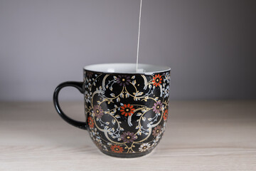 Tea bag put in black teacup with painting