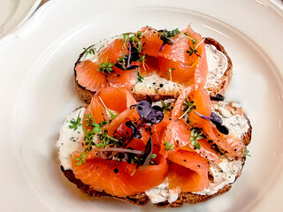 Bruschetta with lightly salted salmon and buttercream are on a plate.