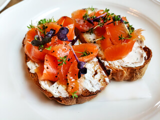 Bruschetta with lightly salted salmon and buttercream are on a plate.