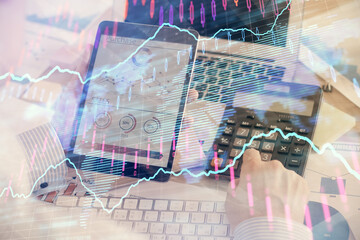 Double exposure of man's hands holding and using a digital device and forex graph drawing. Financial market concept.
