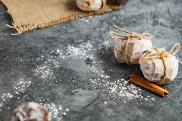 Hot chocolate with cinnamon on sackcloth. Mini doughnuts in the shape of a ball, filled and wrapped in recycled paper. Dark grey marble background. Christmas background. Breakfast.