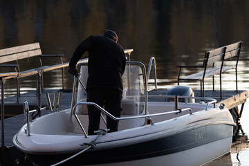 Middle aged man cleaning a boat on a lake next to a deck