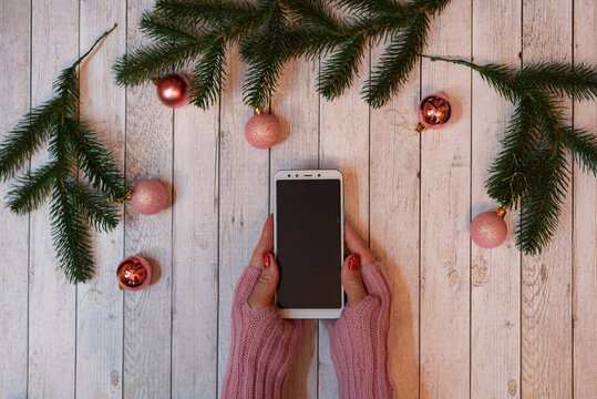 Female holding smartphone. christmas decoration on wooden background
