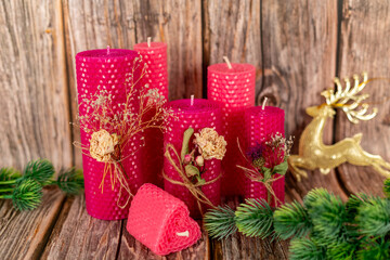 Handmade pink honey candles made of natural wax on a background of wooden boards. Elements from natural materials. Christmas or New Year's composition. Photo for postcards.