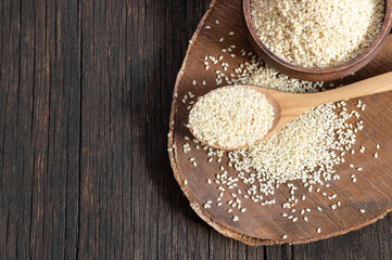 Raw sesame seeds in wooden shovel on wooden rustic table. Uncooked sesame background concept with copy space