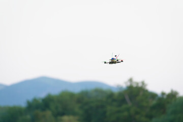 Home made racing quad copter FPV camera drone banks to fly past.