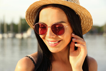 Beautiful young woman wearing stylish sunglasses near river