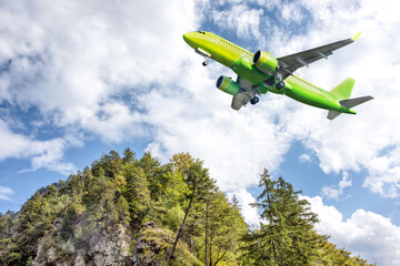 Fototapeta na wymiar A big yellow jet flying over beautiful high mountains.