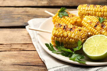 Tasty grilled corn on wooden table, space for text