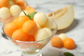 Melon balls and mint in glass on white table, closeup