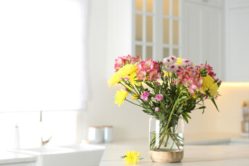 Vase with beautiful flowers on table in kitchen, space for text. Stylish element of interior design