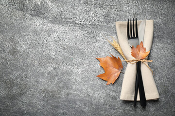 Cutlery and autumn leaves on grey background, top view with space for text. Thanksgiving Day...
