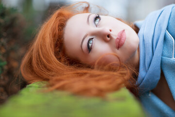 Obraz na płótnie Canvas redhead girl looking up lying down on green