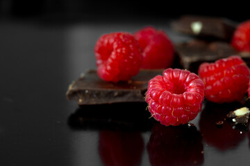Pieces of chocolate and fresh raspberries. Food dessert background.
