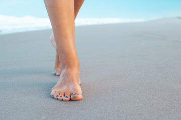 Woman walking on sand beach leaving footprint in the sand.  Beauty, health, skin care concept.