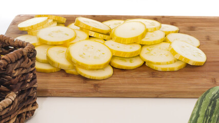 Zucchini slices closeup on wooden cutting board on white background
