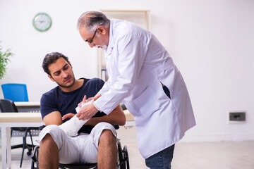 Obraz premium Young injured man visiting experienced male doctor traumatologis