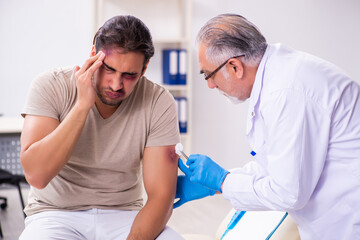 Obraz premium Young face injured man visiting experienced male doctor traumato