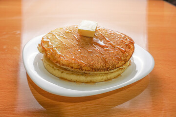 delicious breakfast hot cake with butter and honey on a white plate
