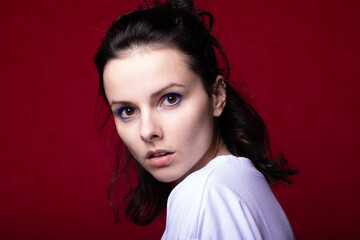 emotional girl in a white t-shirt on a burgundy background