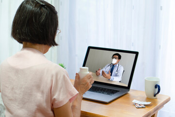 Fototapeta na wymiar senior patient who got fever and cough consult asian doctor about medication via video call. telemedicine and new normal lifestyle concept