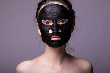 woman doing self-care, black cosmetic mask against acne