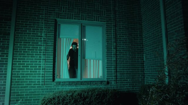 paranoid man looking out of window