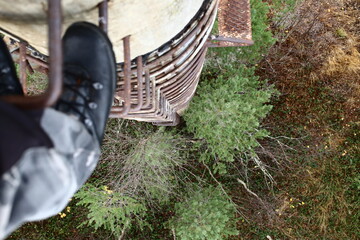 Looking down from a rusty ladder at an old concrete pillar