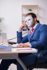 Male employee with mask in hipocrisy concept