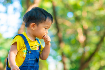 Toddler asian boy playing in city public park on green grass