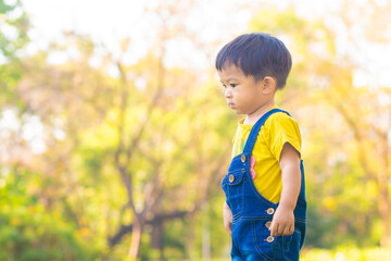 Toddler asian boy playing in city public park on green grass
