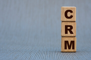 CRM - word on wooden cubes on a gray background